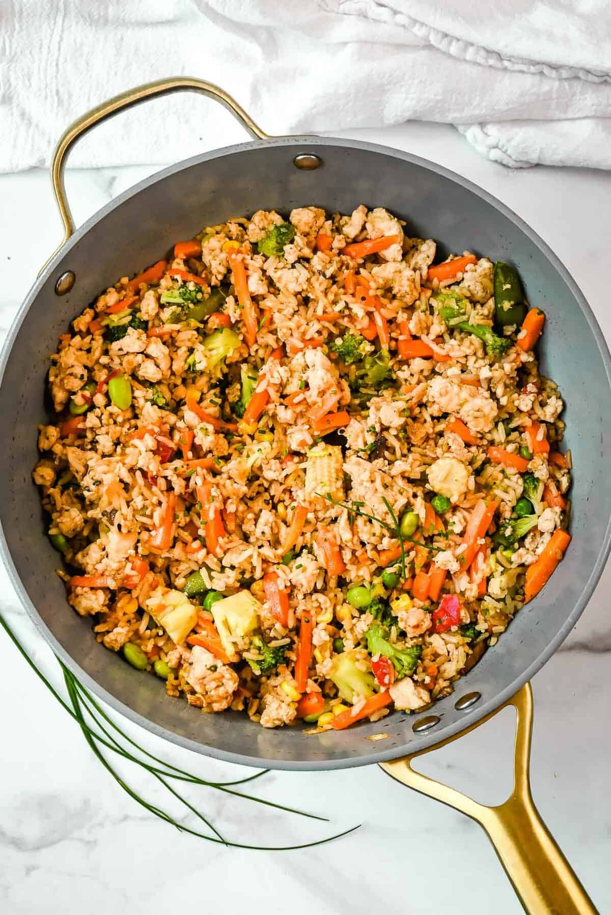 full shot of ground chicken stir fry in a pan on a white background.