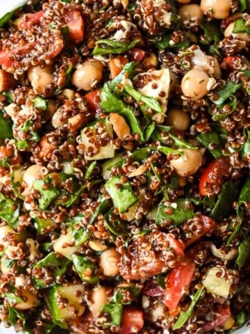 close up shot of spinach quinoa salad topped with fresh herbs and veggies.