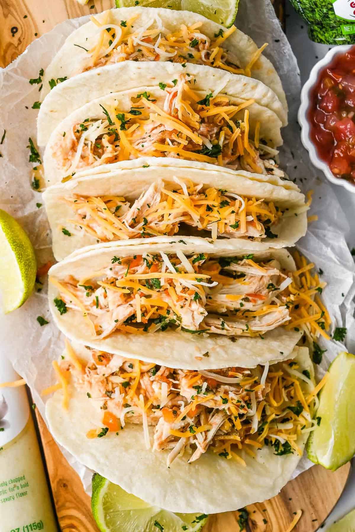 line of chicken tacos topped with shredded cheese