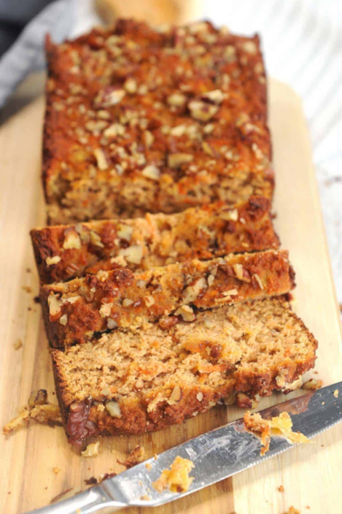 slices of carrot cake bread on a wooden board with a knife.