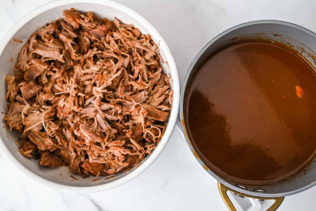 shredded crock pot pulled pork next to bbq sauce in a pan.