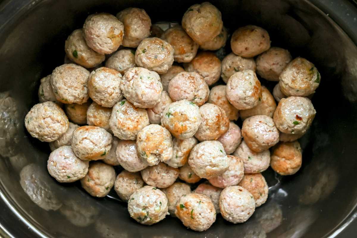 uncooked meatballs in a crock pot.