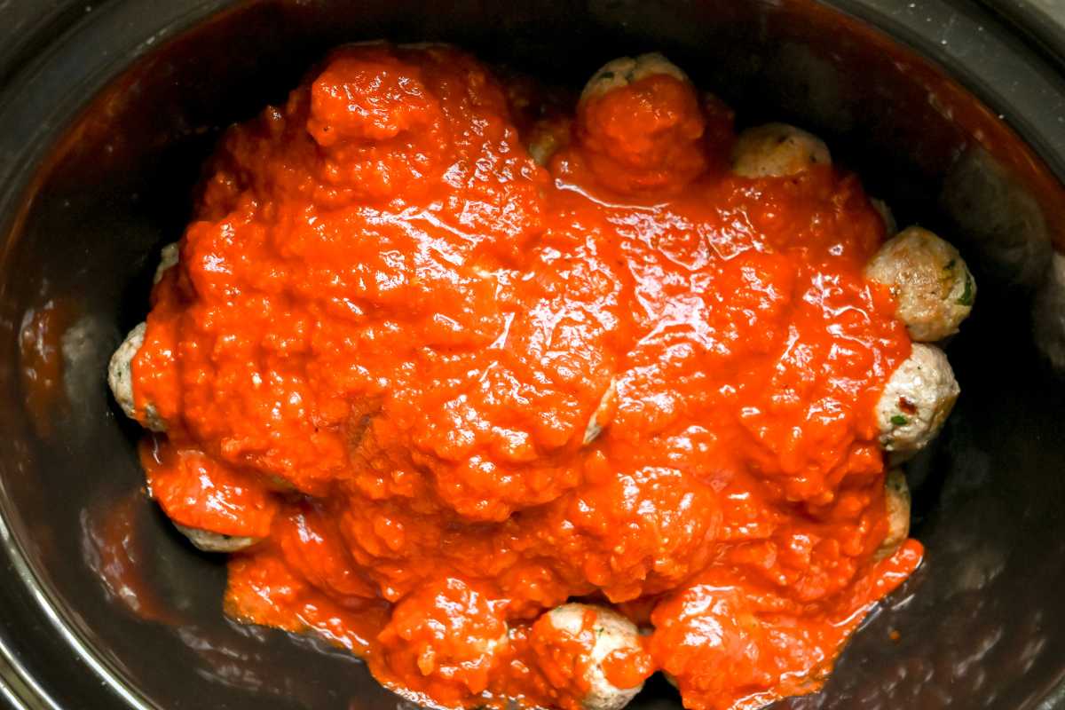 uncooked meatballs in a crock pot covered with sauce.