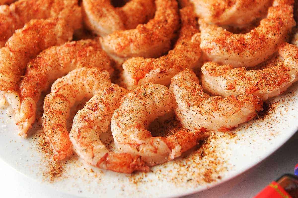 close up shot of argentine red shrimp with seasoning on a white plate, uncooked.