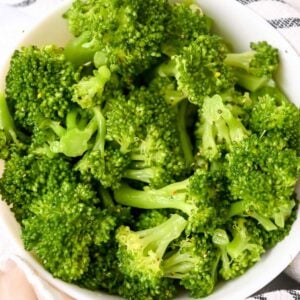 close up of steamed broccoli in a white dish.
