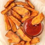 air fryer potato wedges laying on parchment paper with ketchup