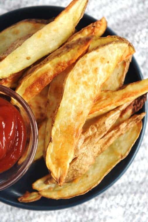 air fryer potato wedges on a plate with ketchup