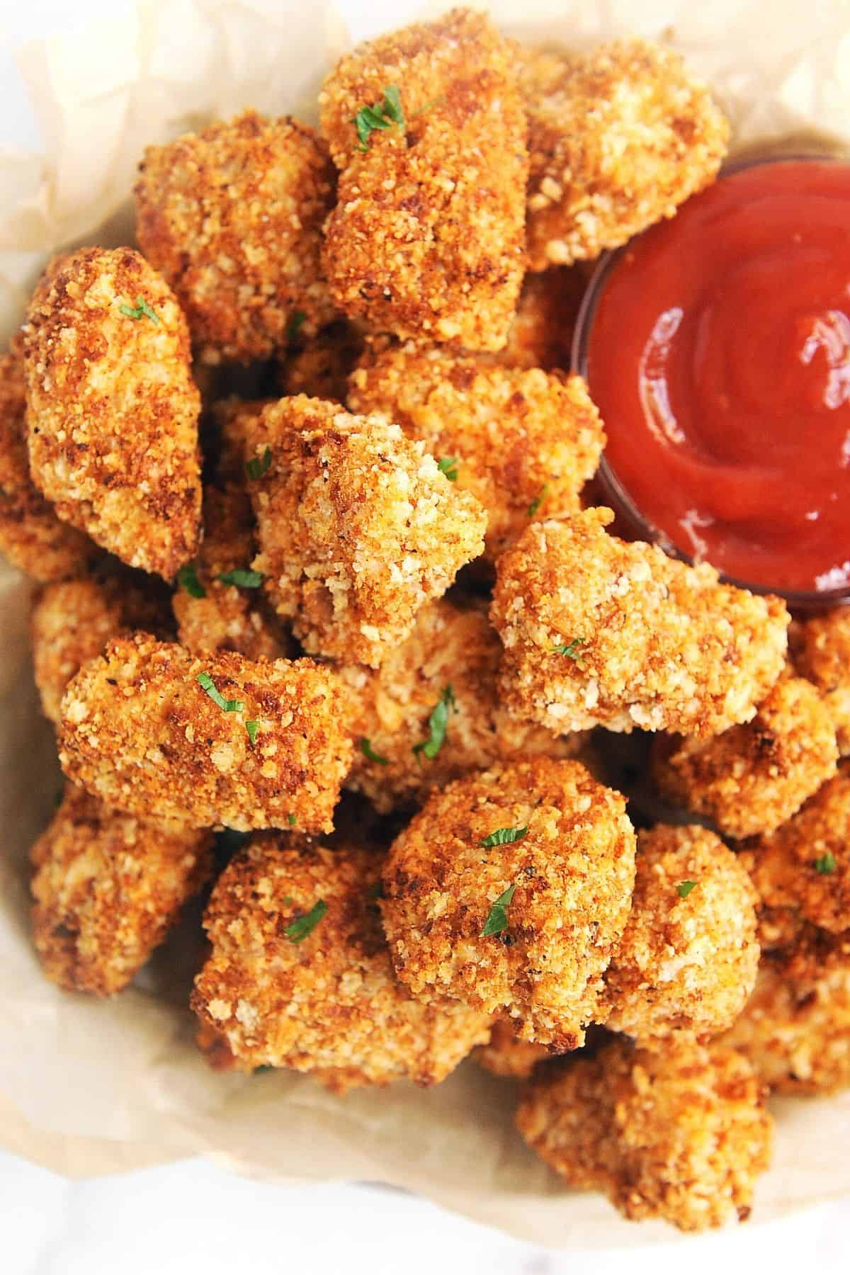 air fryer chicken nuggets with crispy breading in a pile with ketchup