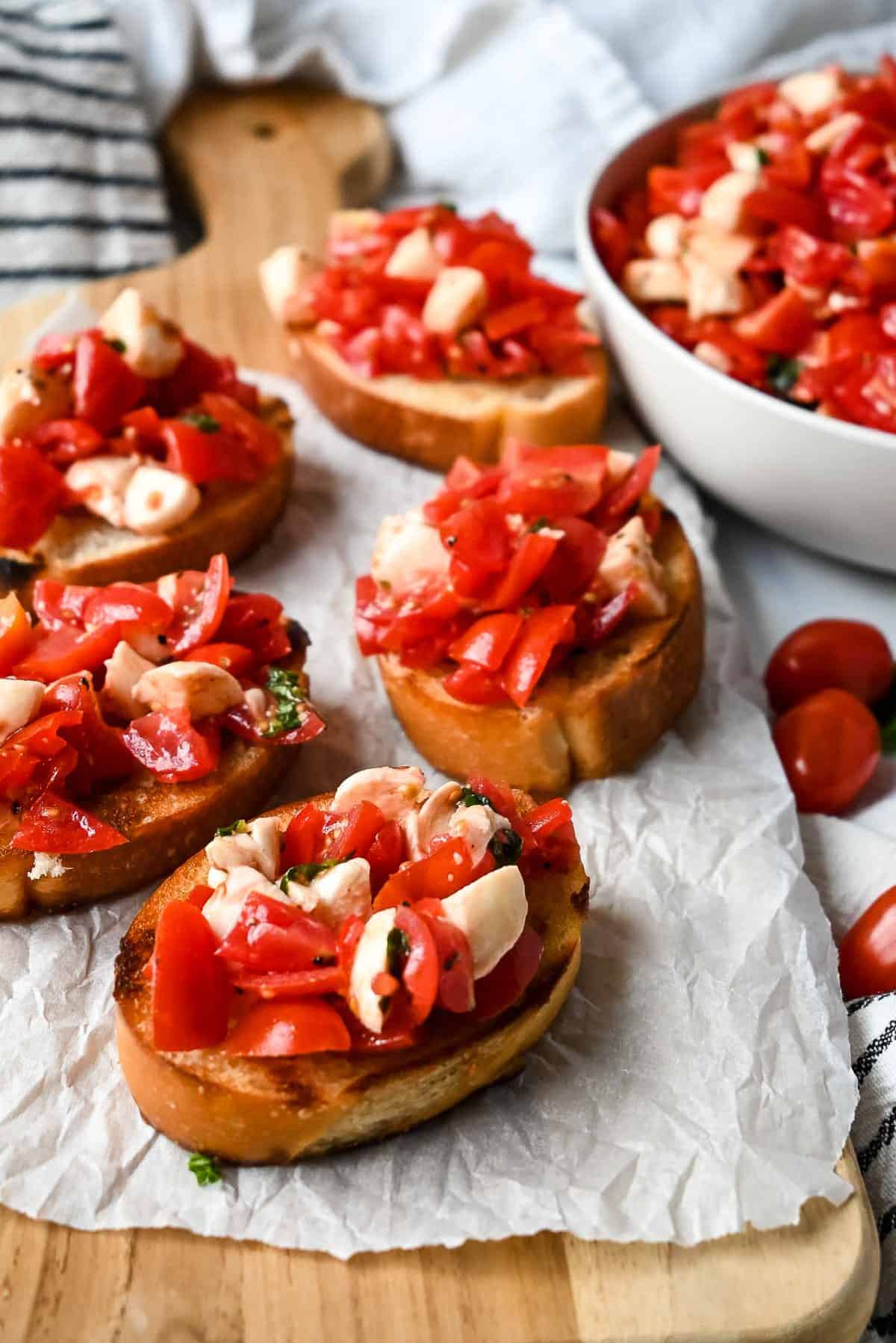 pieces of bruschetta on top of parchment paper on a wooden board