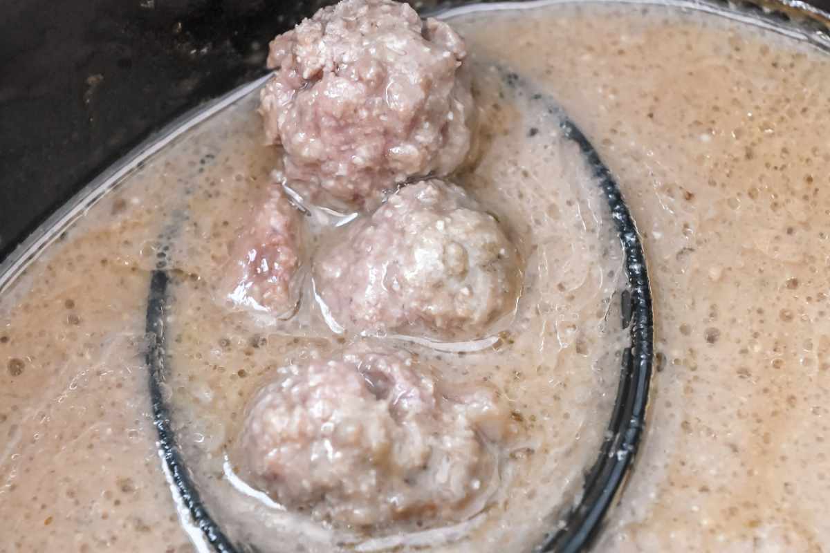 cooked meatballs in gravy on a spoon.