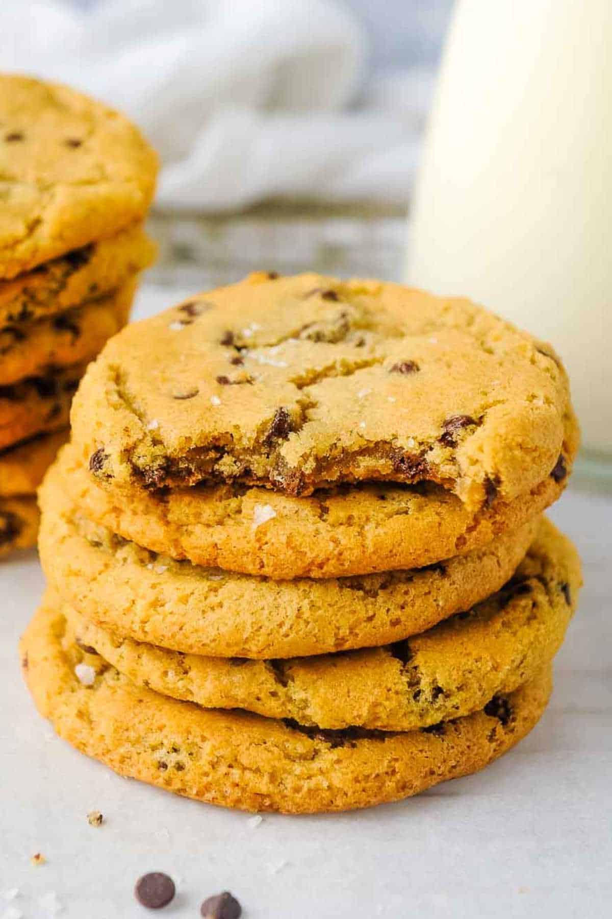 stack of small batch chocolate chip cookies with bite shot and milk behind.