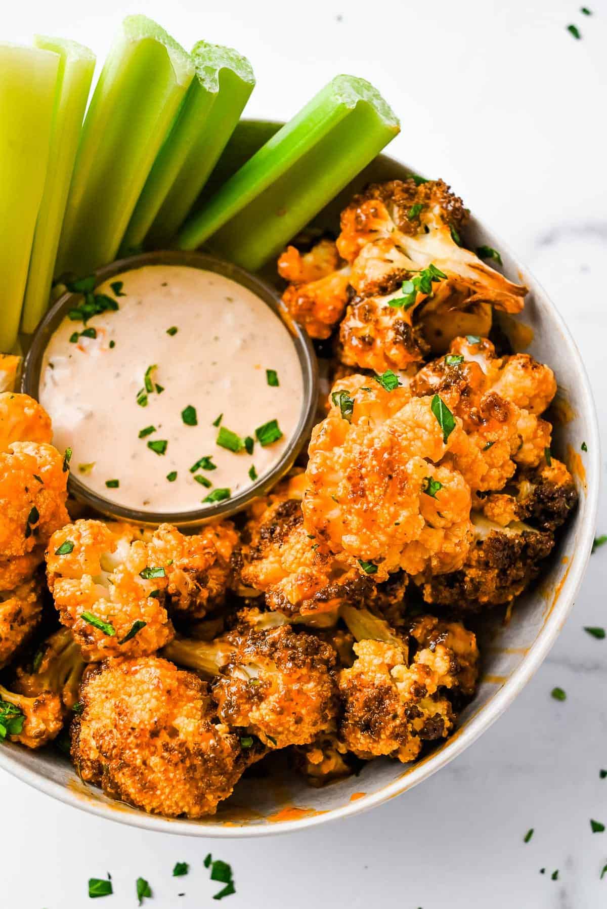 air fryer buffalo cauliflower topped with parsley with ranch dressing