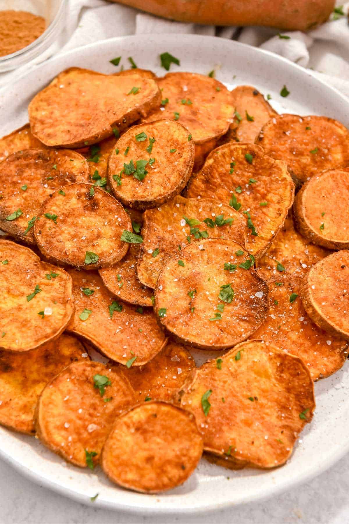 plate of air fryer sweet potato rounds topped with parsley and salt.