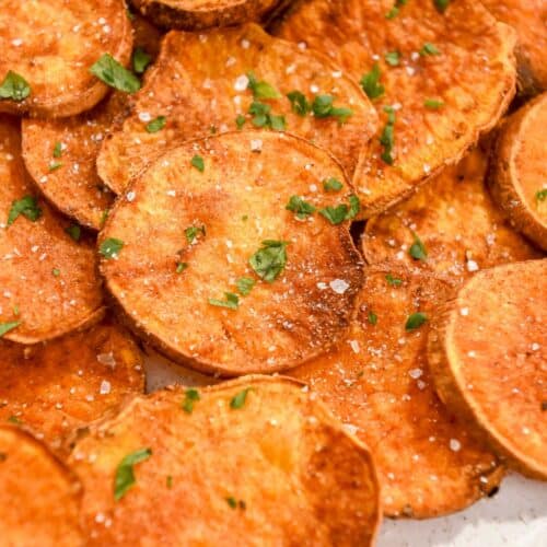 close up photo of air fryer sweet potato rounds topped with parsley and salt.