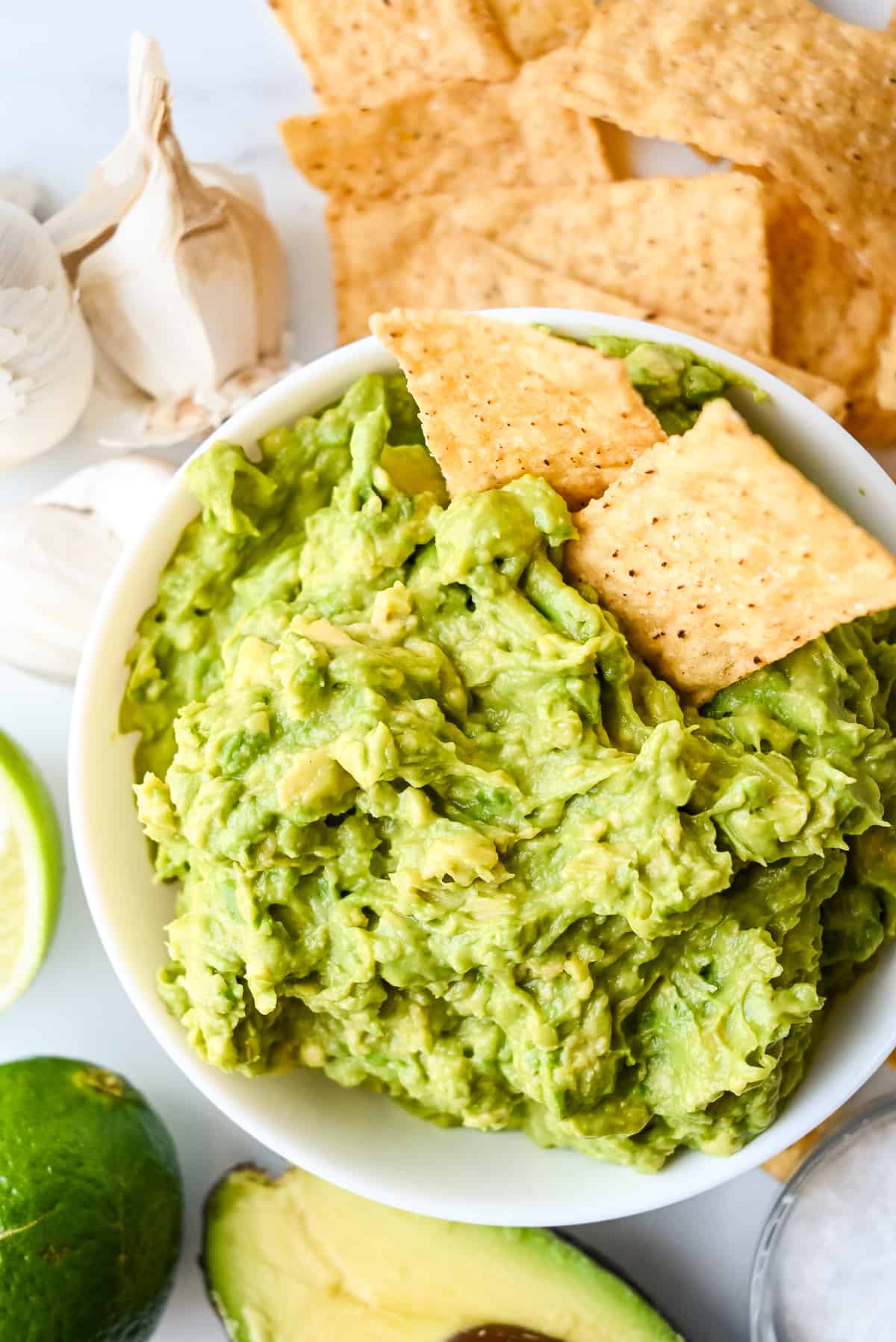 bowl of guacamole with no onions, cilantro or tomatoes in a white bowl with tortilla chips.