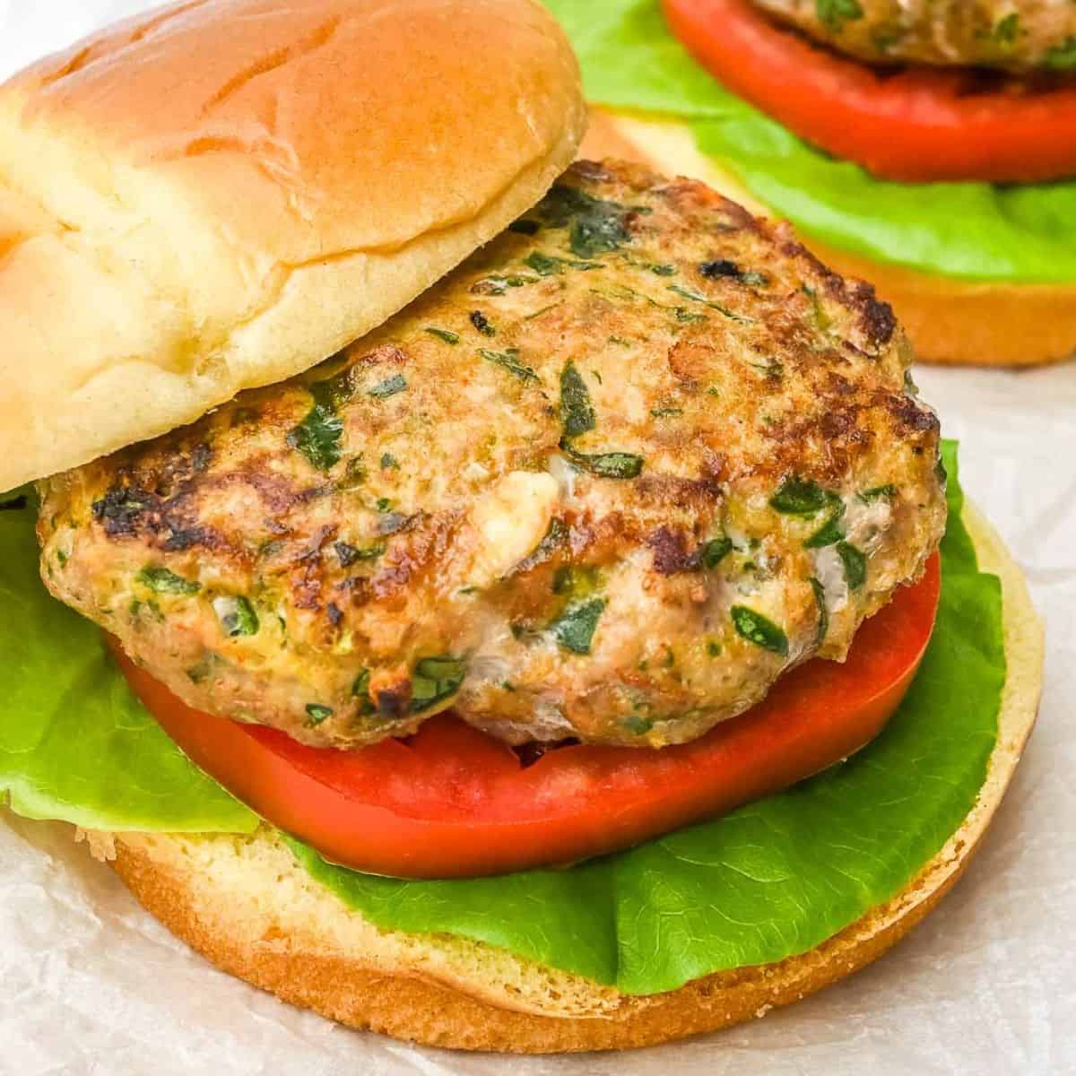 close up of turkey burger on a bun with lettuce and tomato with top bun offset.