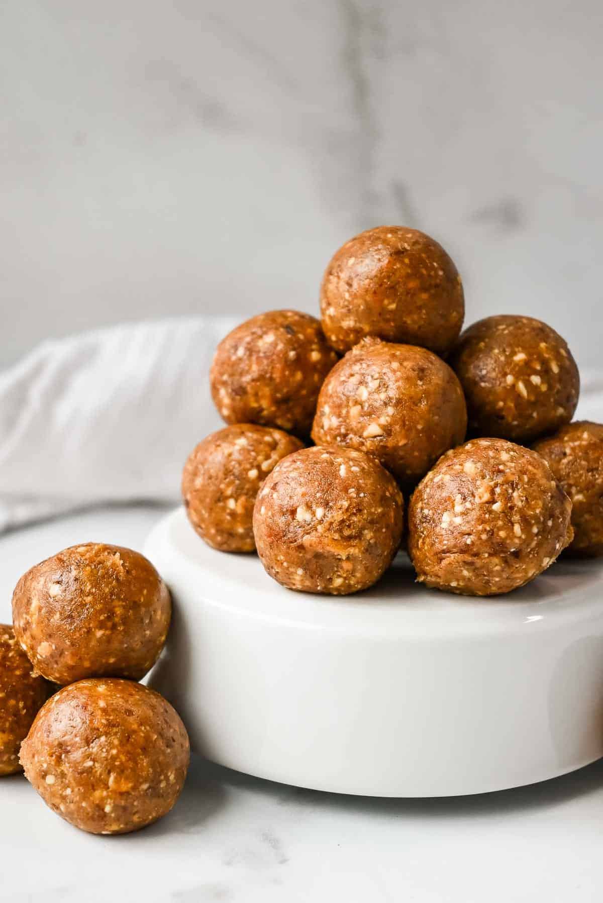 protein date balls in a stack on a white dish