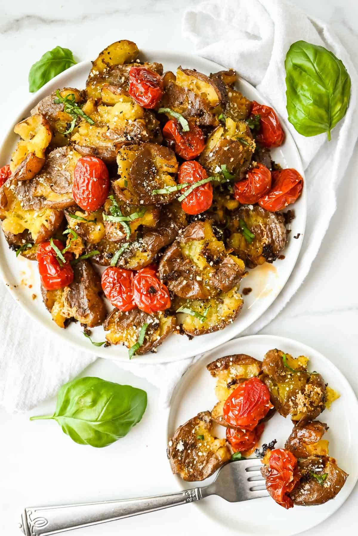 plate of smashed red potatoes with basil and tomatoes