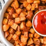 close up featured image of air fryer red potatoes in a white bowl with a side of ketchup.