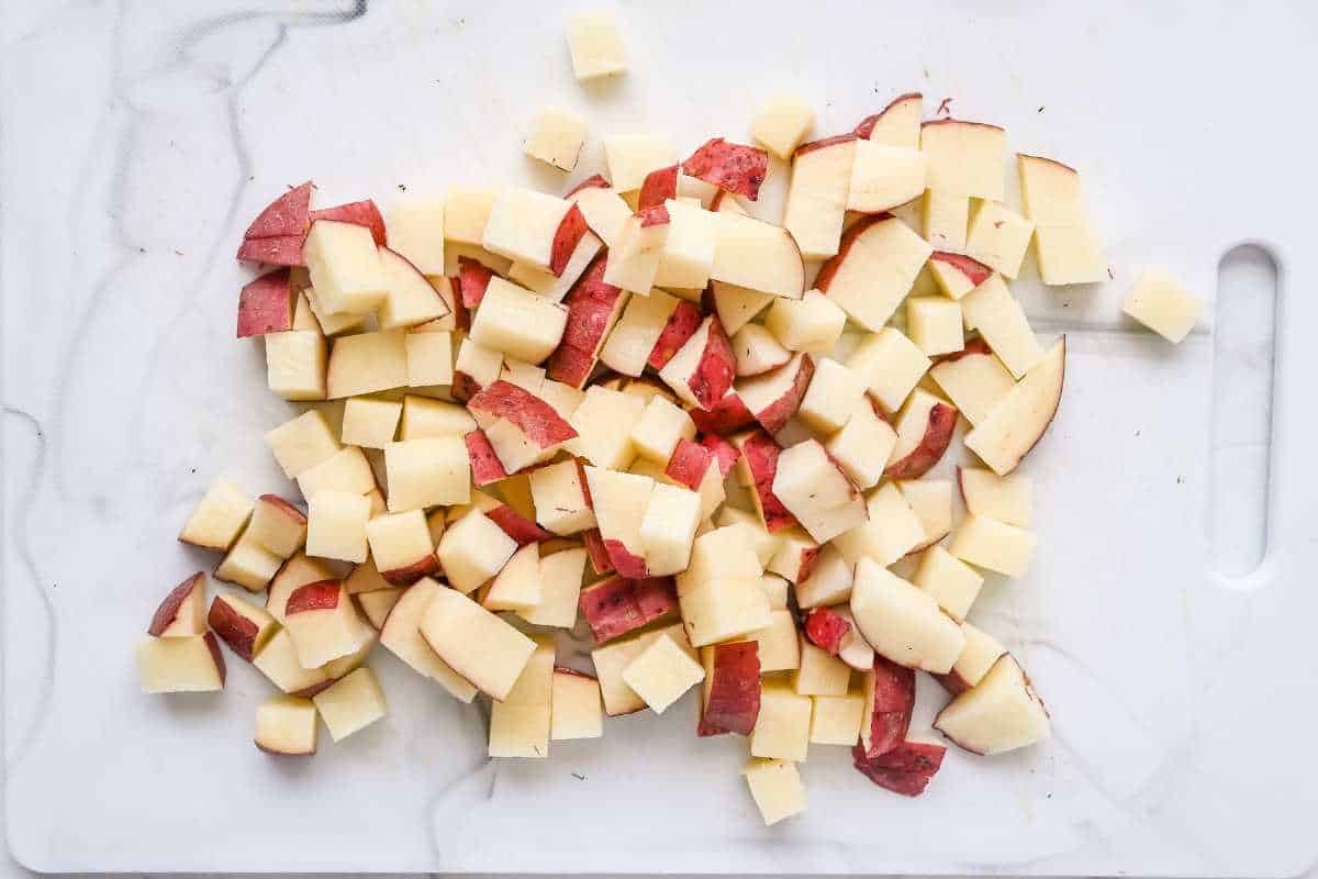 diced red potatoes on a white cutting board.