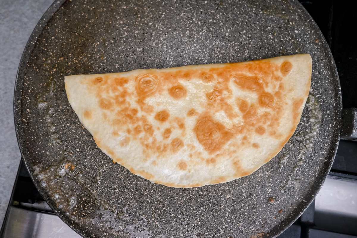 folded tortilla on a gray pan on the stove.