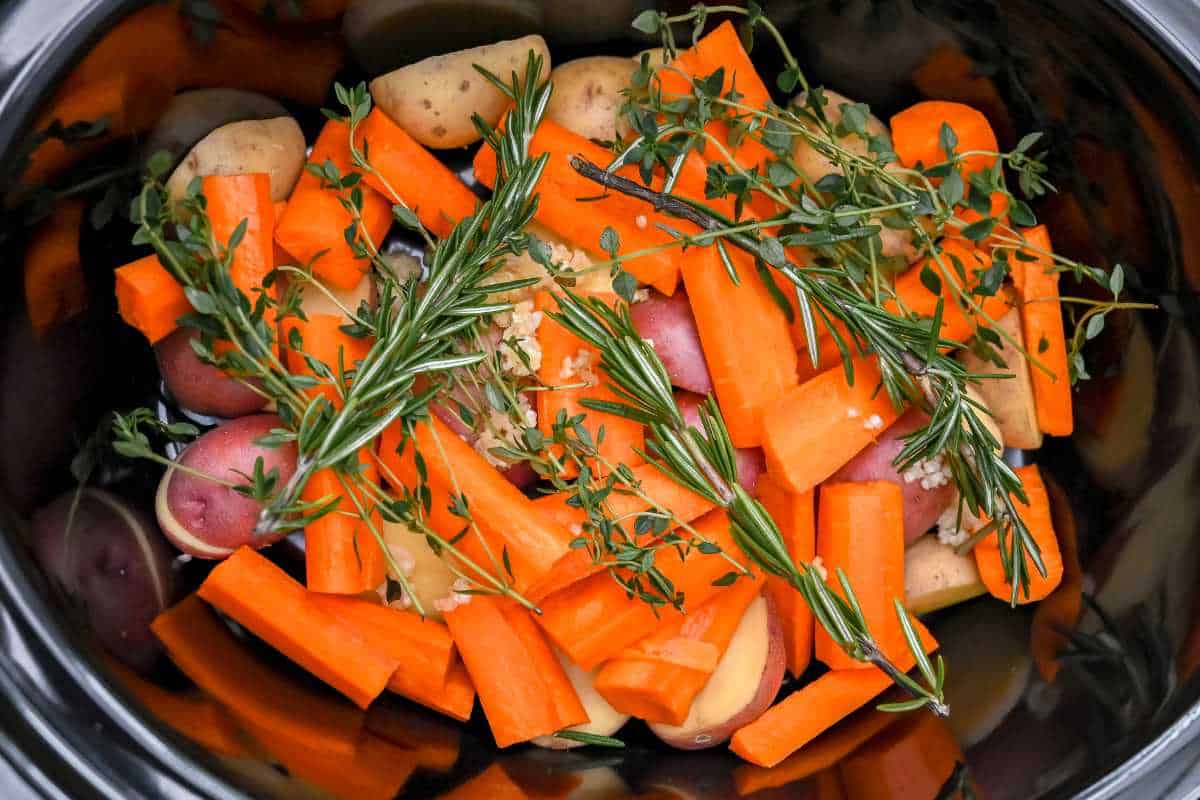 vegetables and herb s in a crock pot.