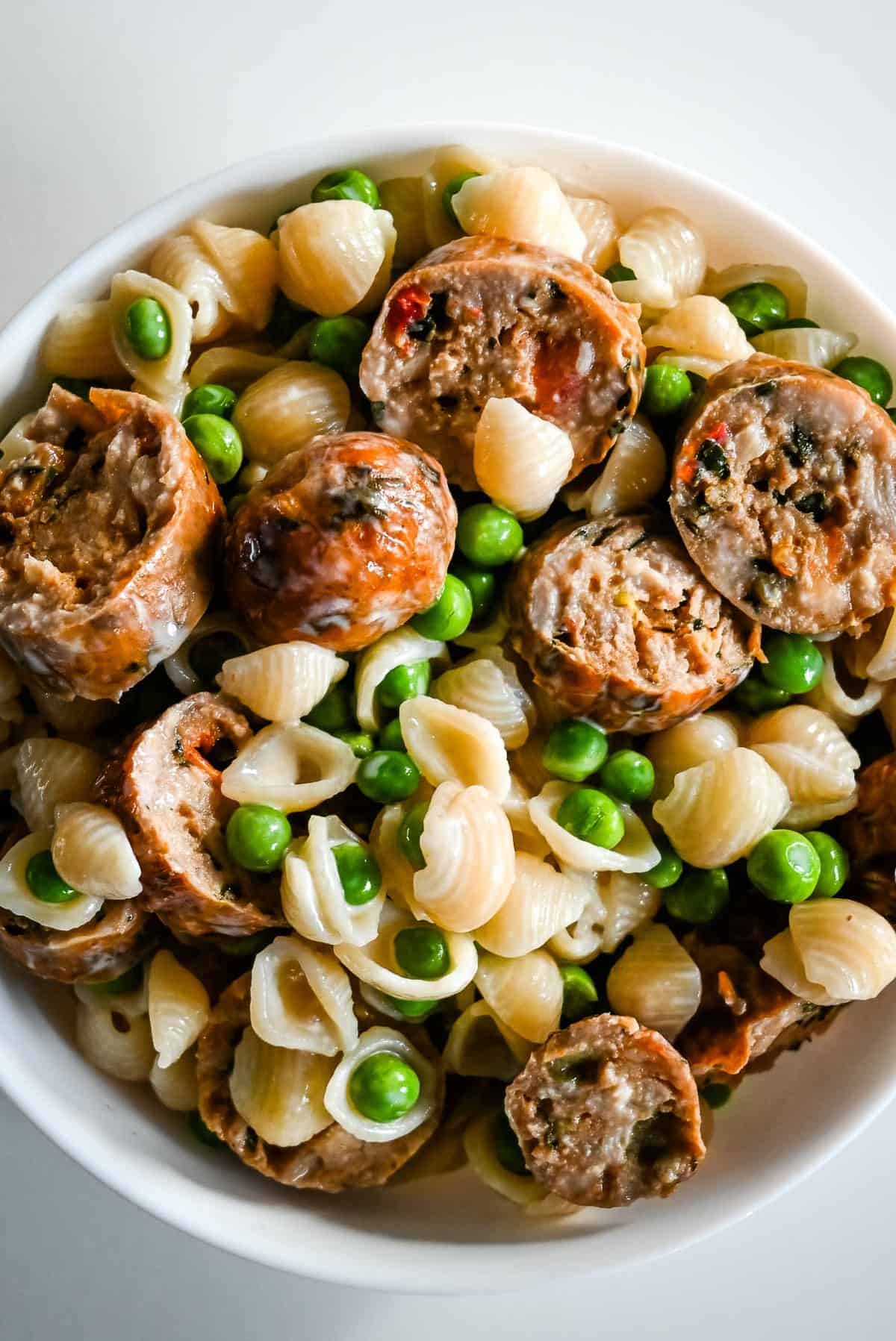 bowl of air fryer sausage with macaroni and cheese and peas.