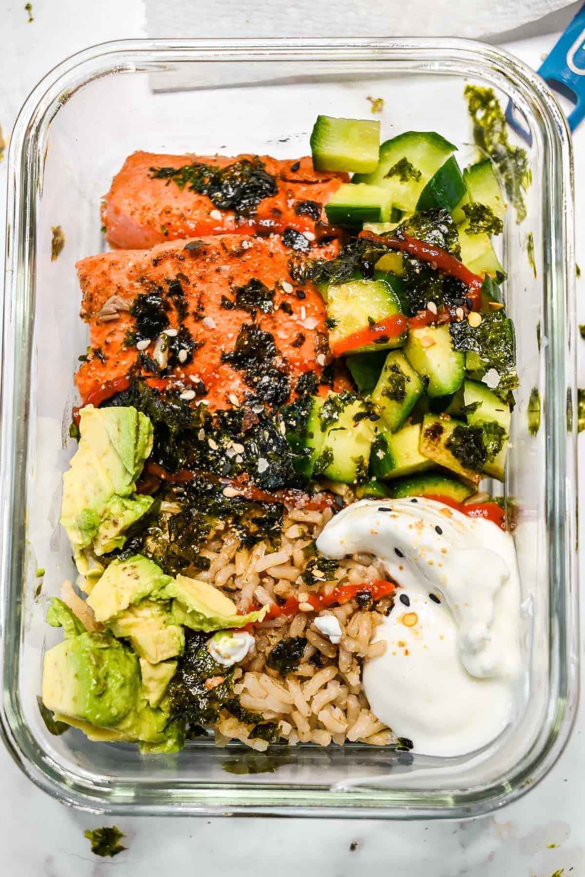 meal prep container full of cooked salmon sushi bowl ingredients.