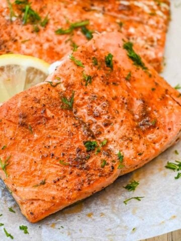 close up shot of old bay salmon topped with dill and with lemon.