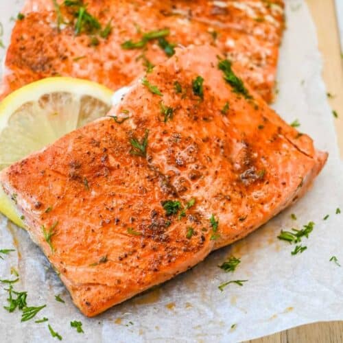 close up shot of old bay salmon topped with dill and with lemon.