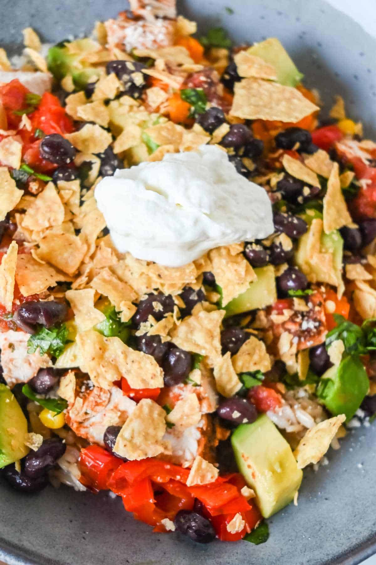 southwest chicken bowl topped with tortilla chips, black beans, and sour cream.