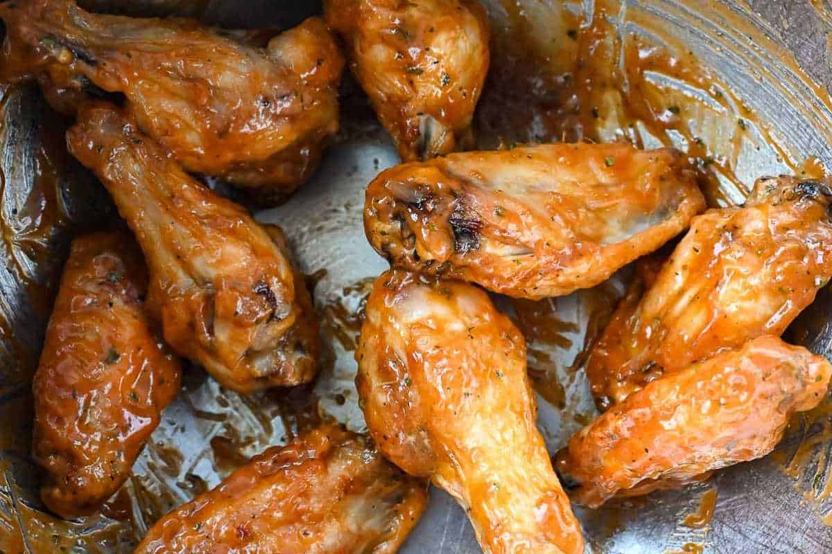 close up shot of chicken wings getting sauce on them.