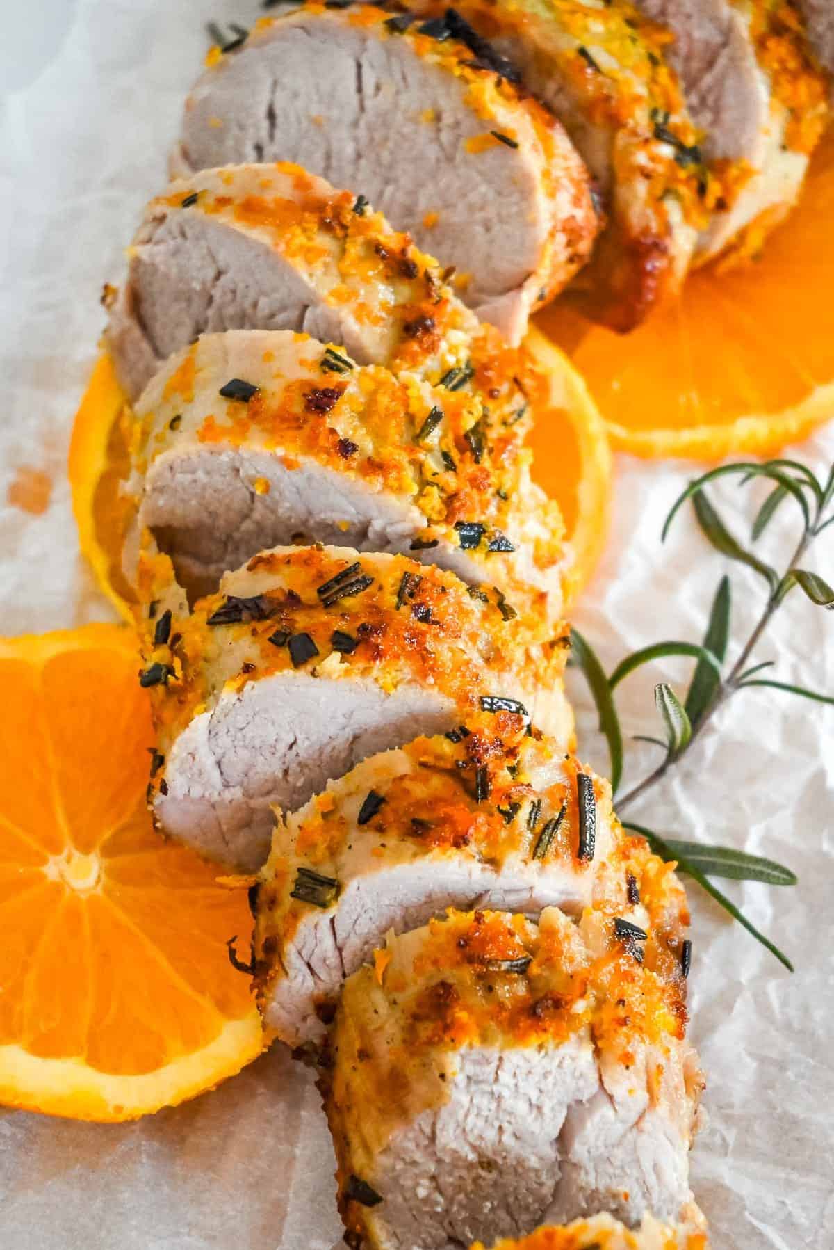 close up shot of air fryer pork tenderloin with oranges and rosemary