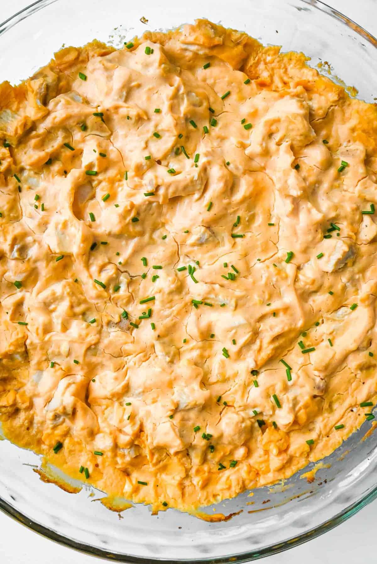 full shot of healthy buffalo chicken dip in a glass pie plate topped with chives.
