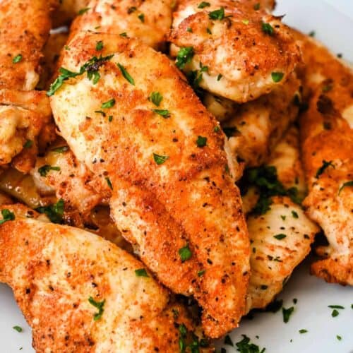 close up shot of air fryer chicken tenders with no breading topped with parsley.