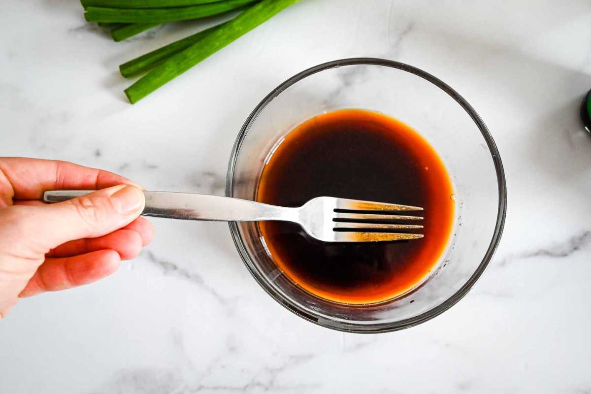 stirring soy sauce marinade in a glass dish.