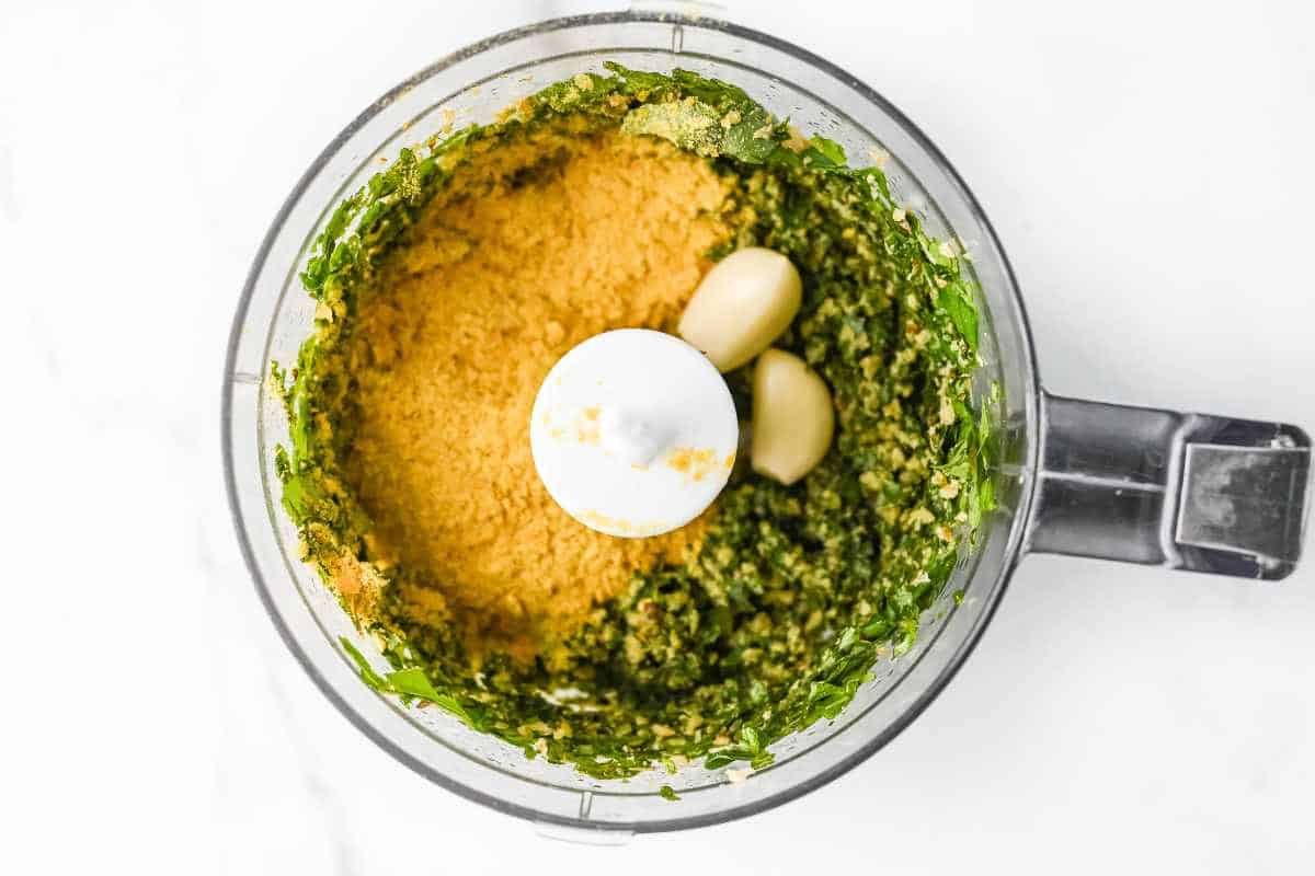pesto ingredients in a food processor on a white background.
