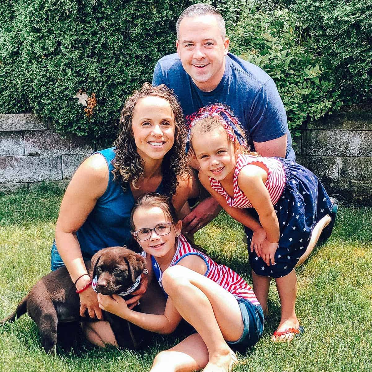 family of four with chocolate lab puppy.