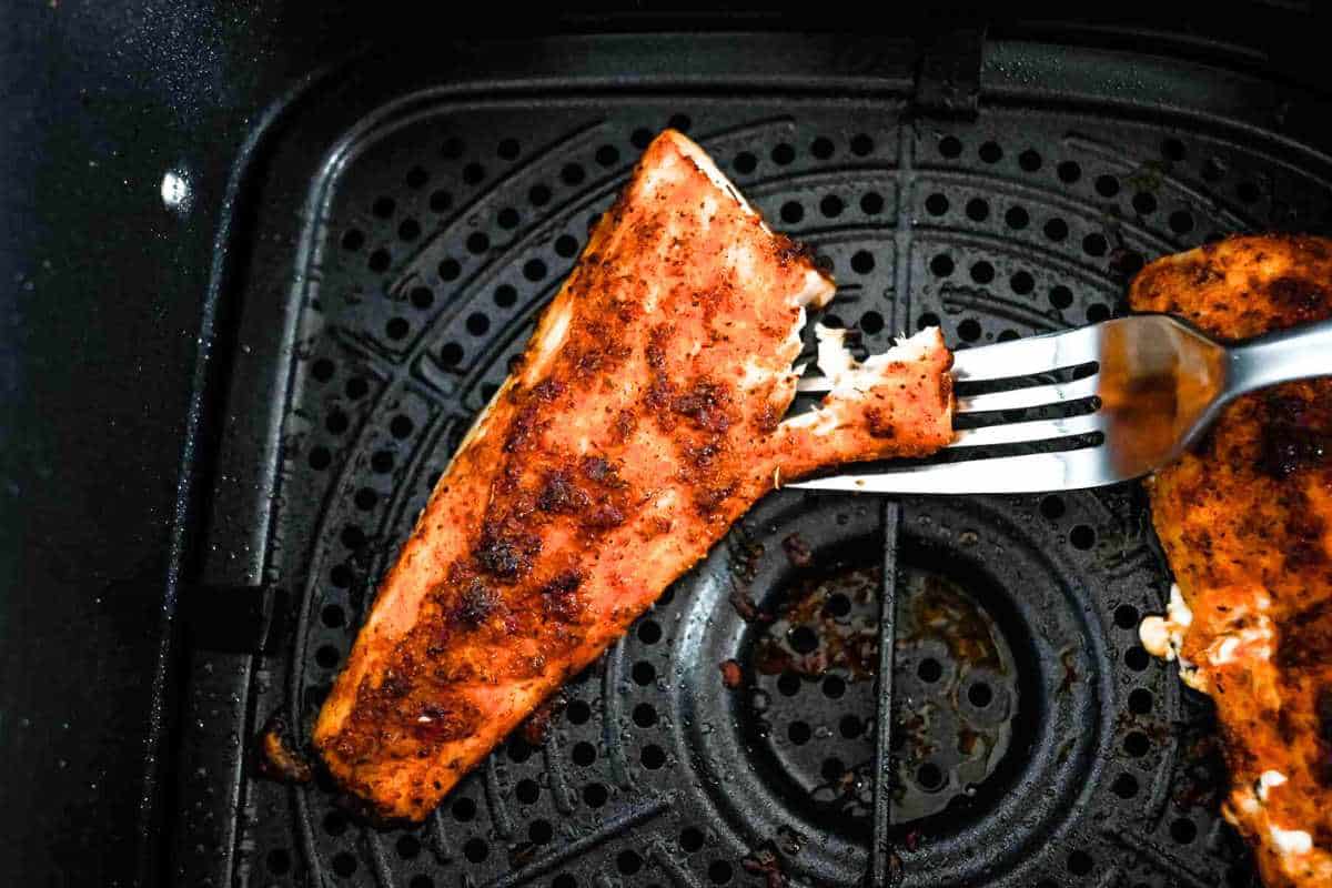 fish flaking mahi mahi in the air fryer to show it is done.