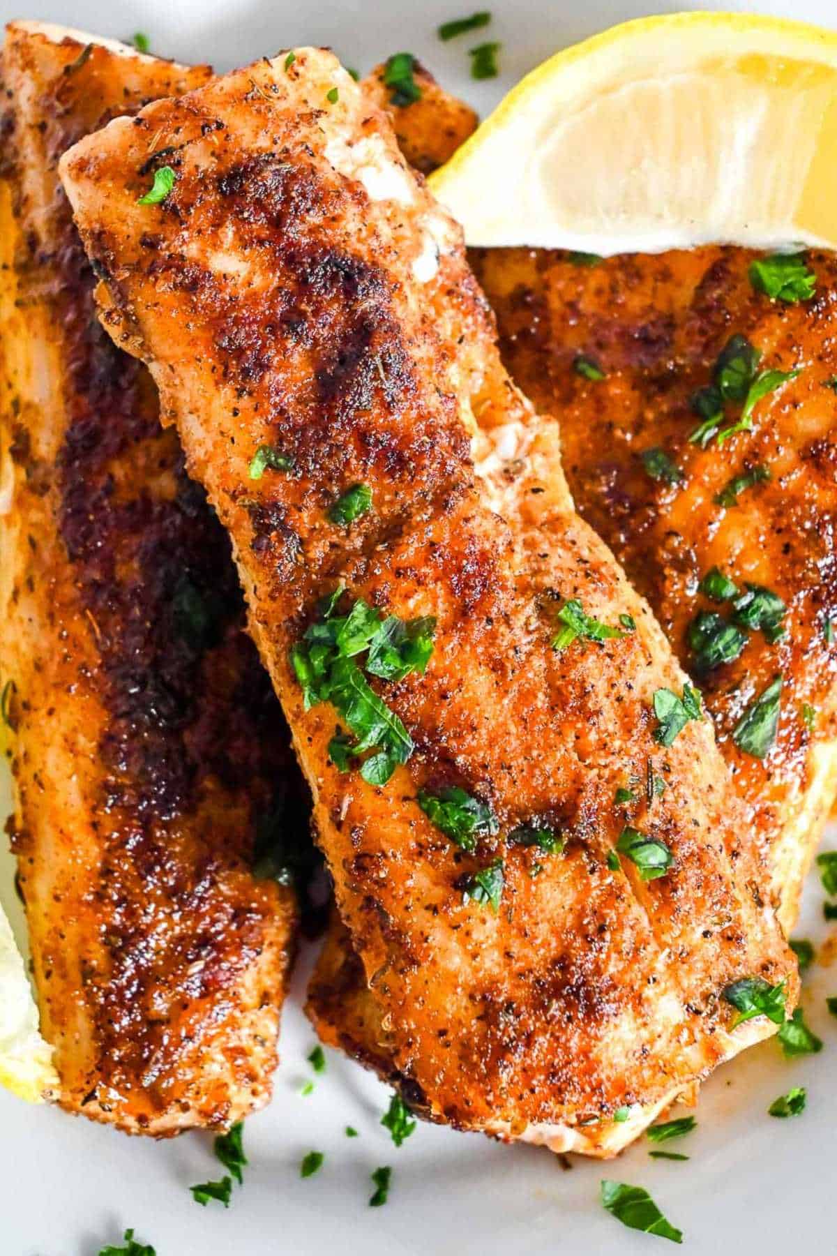 mahi mahi fillets seasoned with cajun spices and topped with parsley and a lemon wedge.