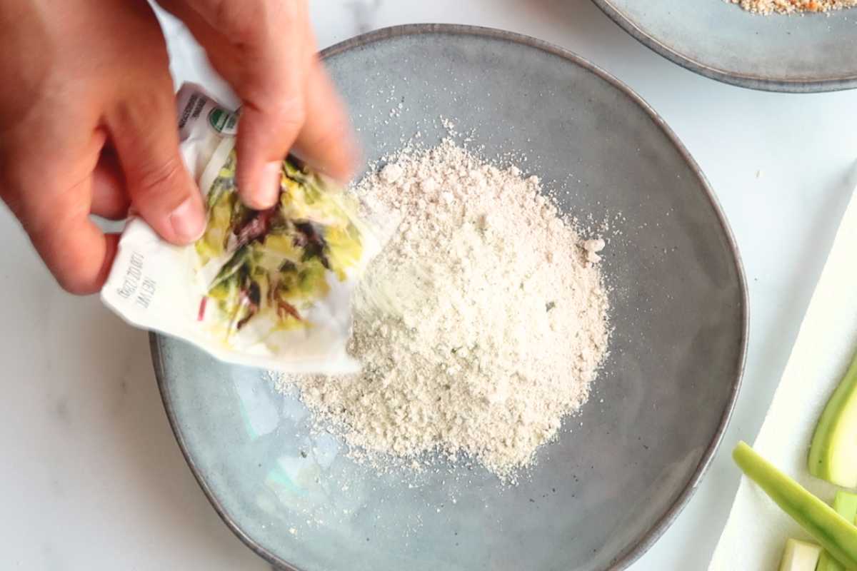 hand pouring ranch dressing into a gray bowl.