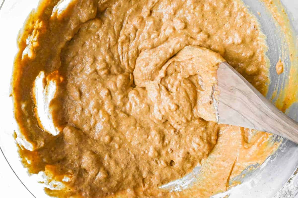 pumpkin banana muffin batter in a bowl with a wooden spoon.