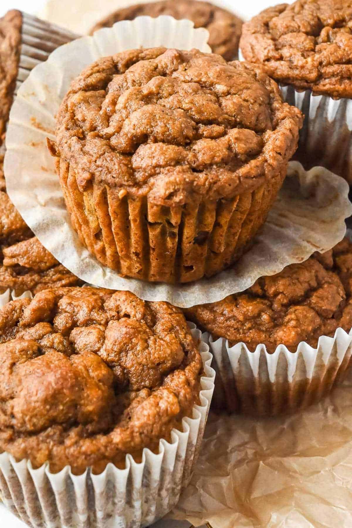 close up of a stack of pumpkin banana muffins, one with theliner removed.