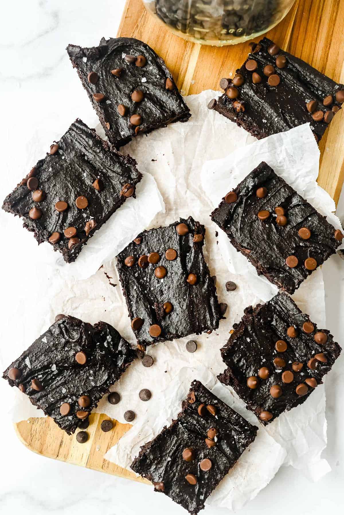slices of sweet potato brownies topped with chocolate chips on a piece of parchment paper.