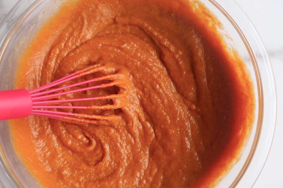pumpkin pie filling with a pink whisk in a bowl