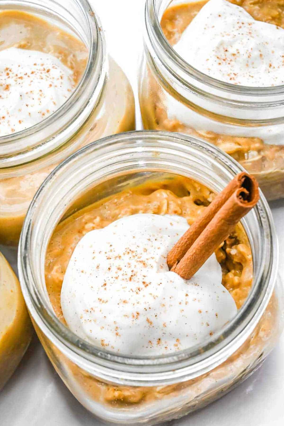 top view of pumpkin overnight oats in a jar topped with Greek yogurt and a cinnamon stick.
