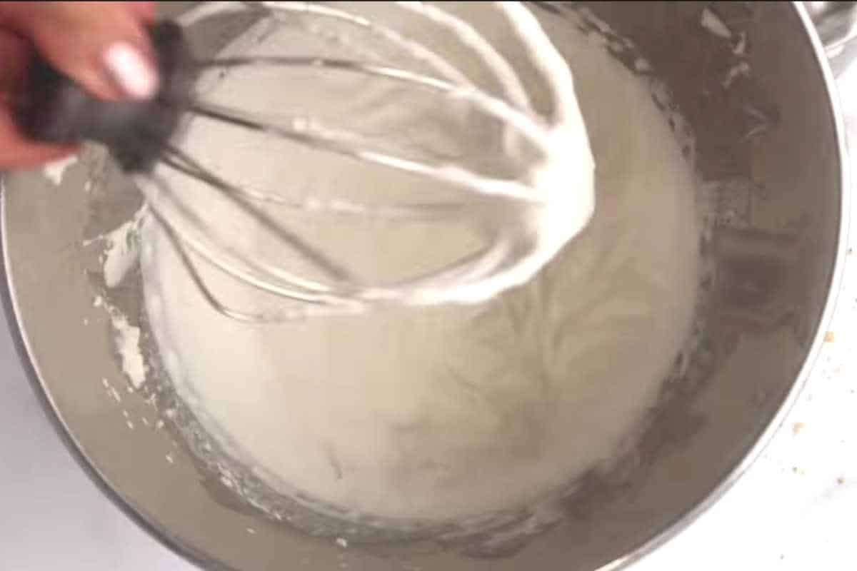 whipped cream in a silver bowl with a whisk.
