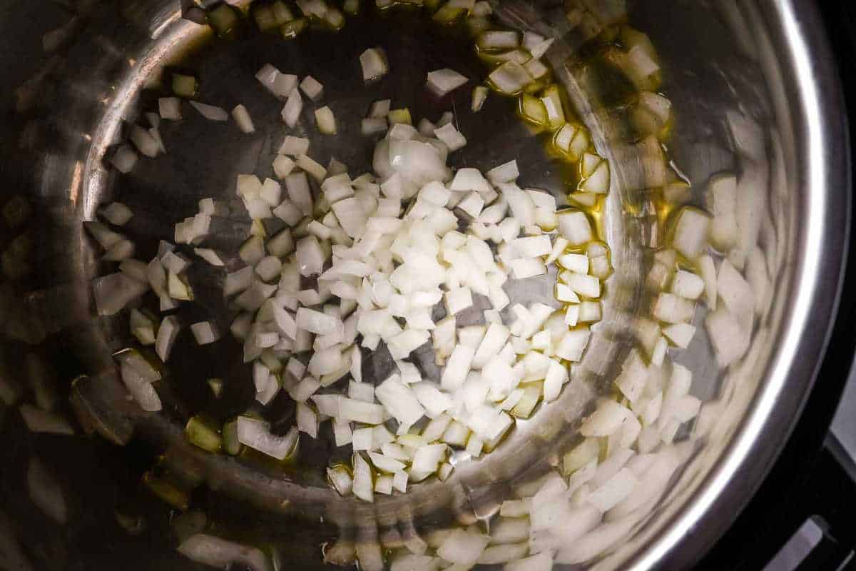 onions sautéing in olive oil in an instant pot.
