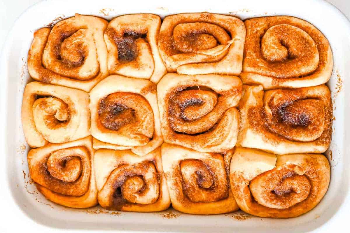 unbaked cinnamon rolls in a white pan.