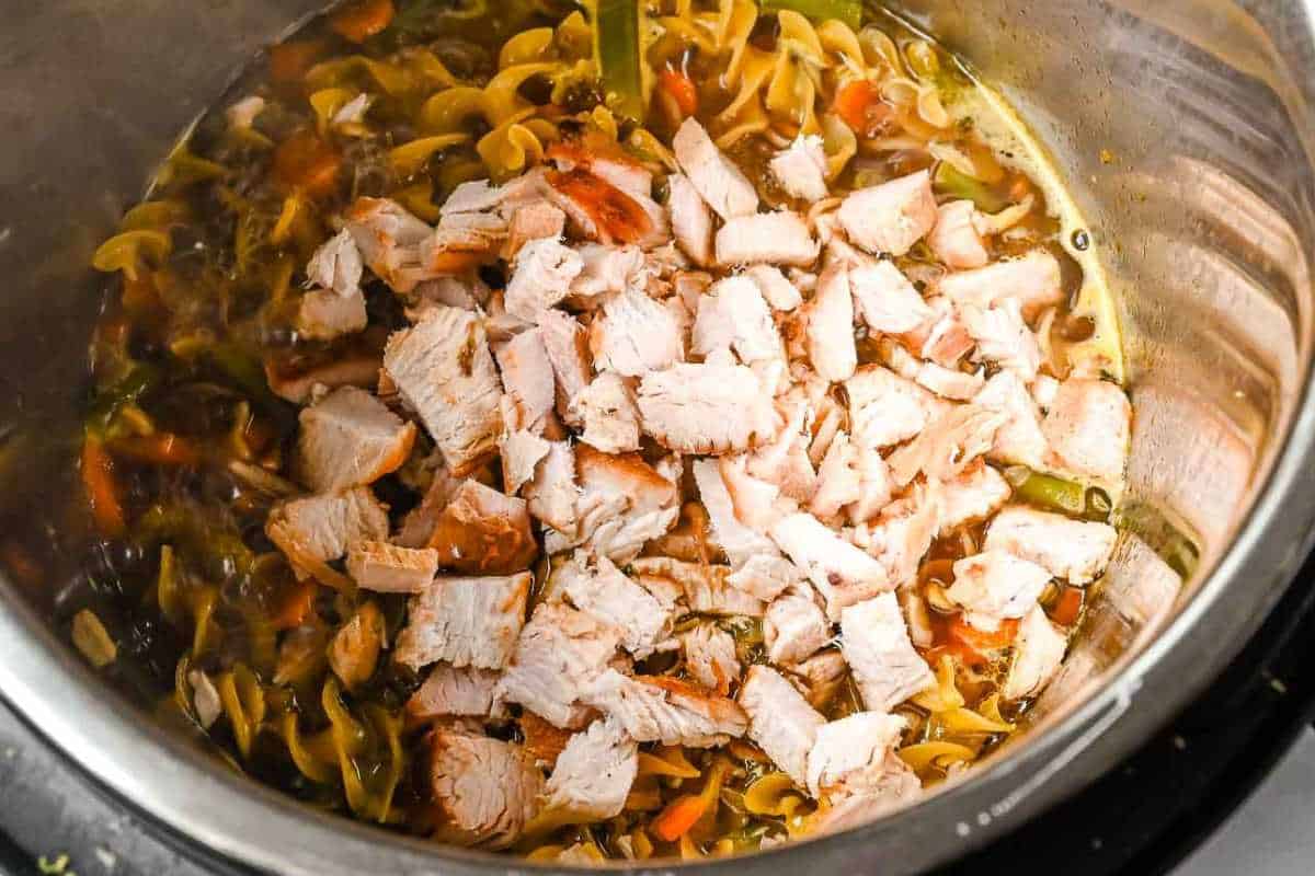 turkey meat on top of noodles, vegetables, and broth in an instant pot.
